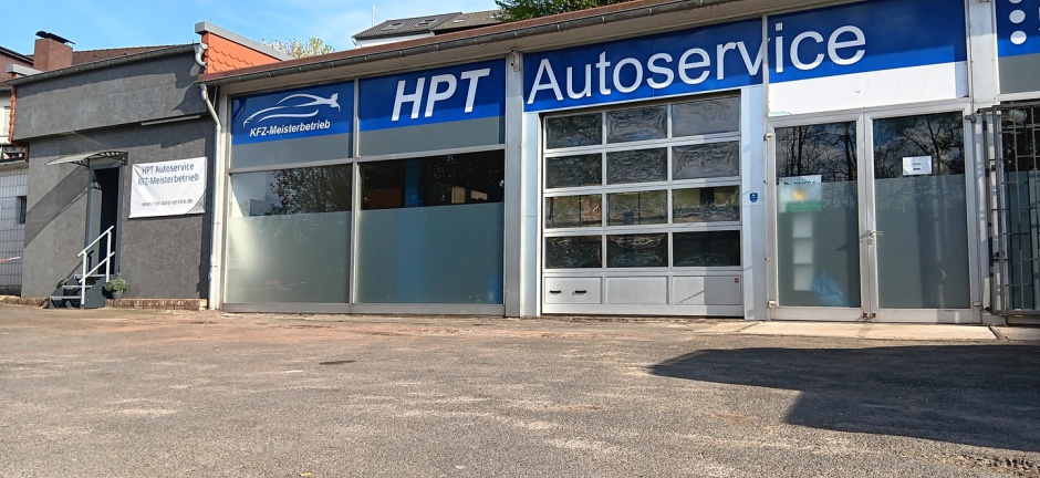 Werkstattgebäude von HPT-Autoservice mit blauem Firmenschild und geöffneten Hallentoren